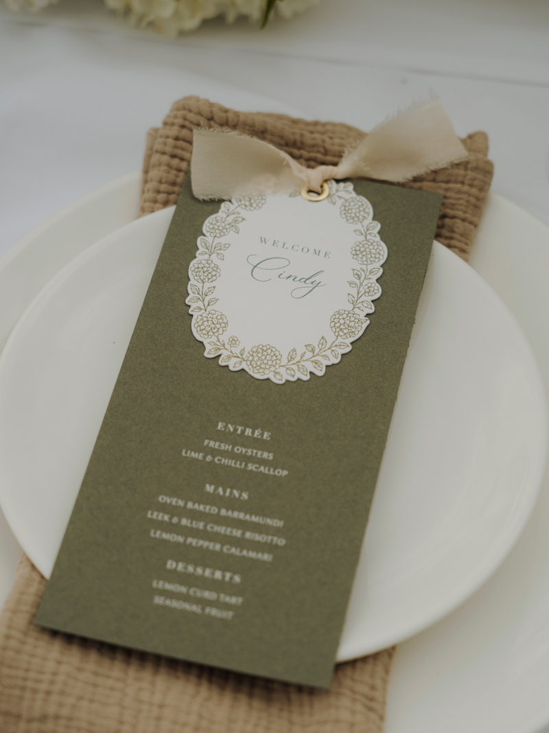Green menu card with decorative bow on a white plate